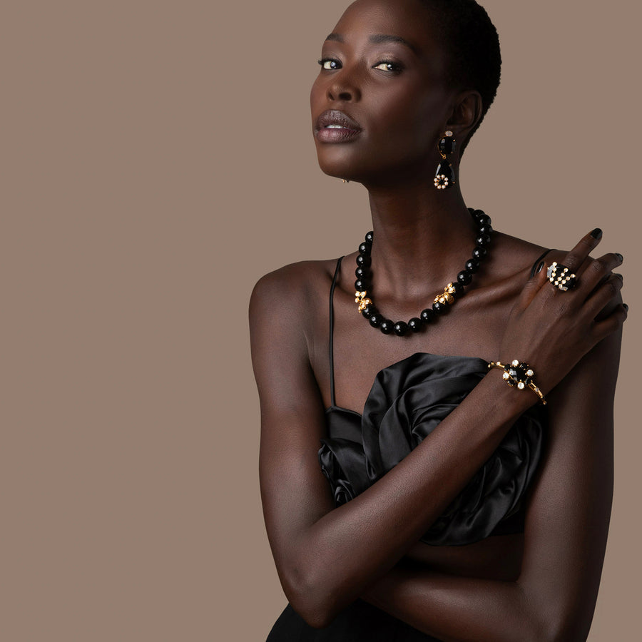 Woman wearing black jewelry against a brown background