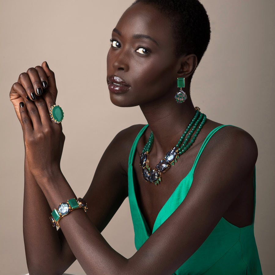 Woman wearing green jewelry against a neutral background