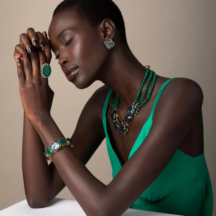 Woman wearing green jewelry against a neutral background