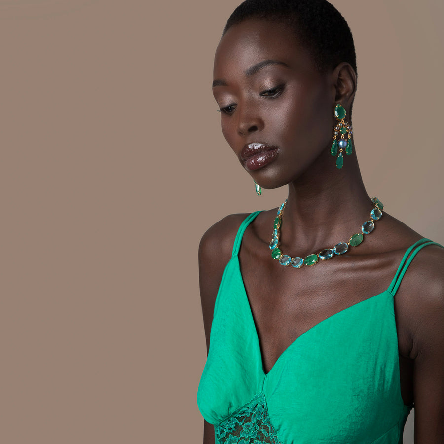 Woman wearing a green dress and jewelry against a brown background