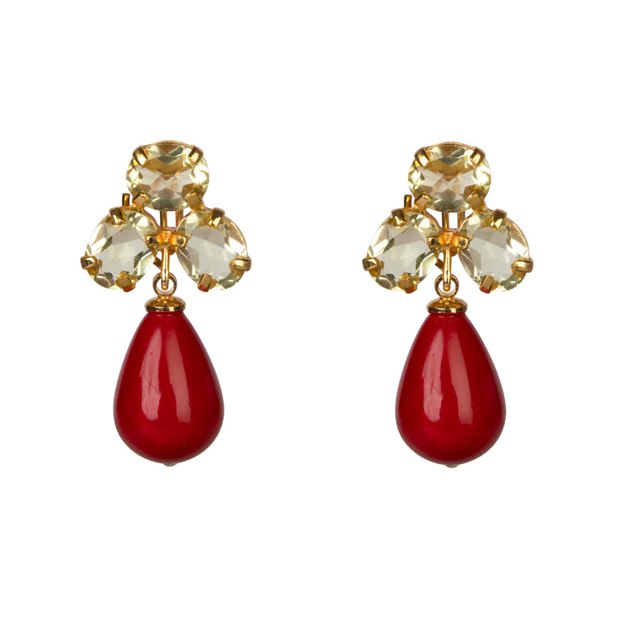Pair of earrings with gold accents and red teardrop stones on a white background