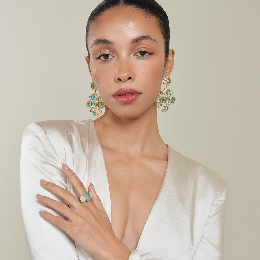 Model wearing Ariadne earrings, highlighting their bold cluster drop design with luminous blue and opal-like stones for an elegant summer statement look.