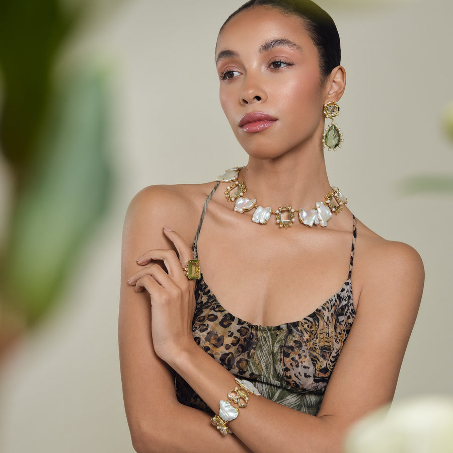 Woman wearing a leopard print dress with gold jewelry against a blurred natural background