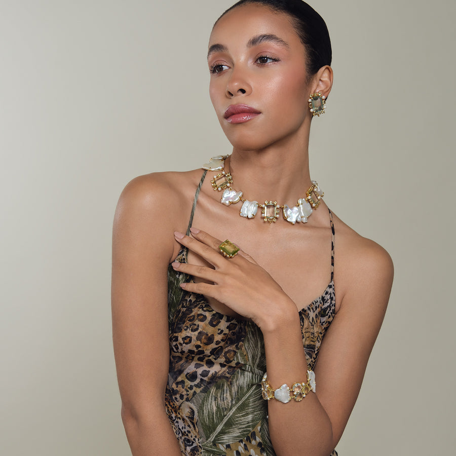 Woman wearing gold jewelry with a neutral background